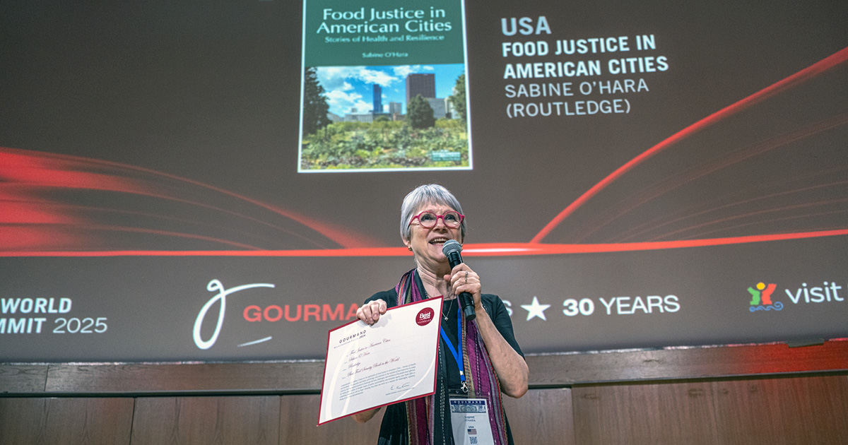 Sabine O'Hara on a stage holding a microphone